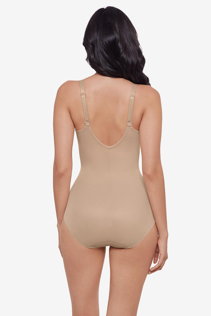 Woman turned away wearing warm beige one-piece shapewear
