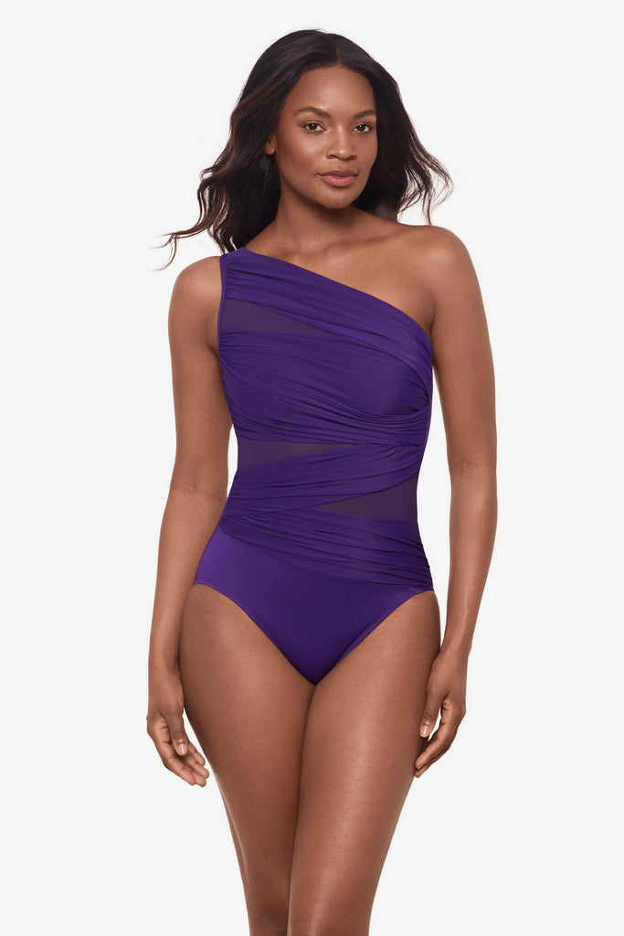 Woman wearing a mulberry purple one-piece swimsuit with a wrap detail and mesh throughout suit