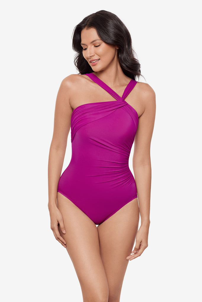 Woman wearing a magenta one-piece swimsuit with an asymmetrical neckline