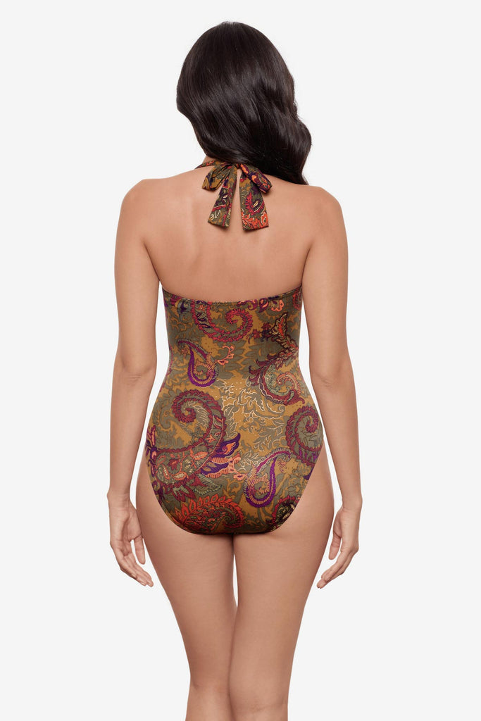 Woman turned away wearing a halter one-piece swimsuit with brown paisley print