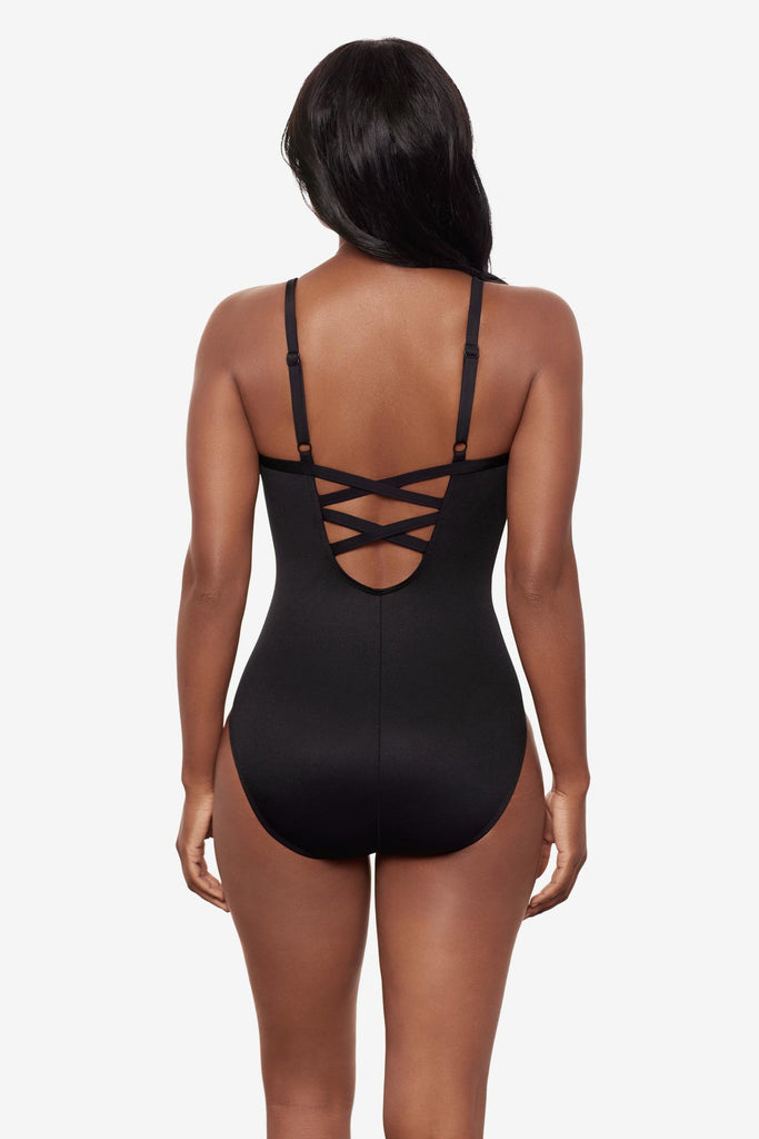 Woman faced away wearing a black and white floral printed one-piece swimsuit with lace back