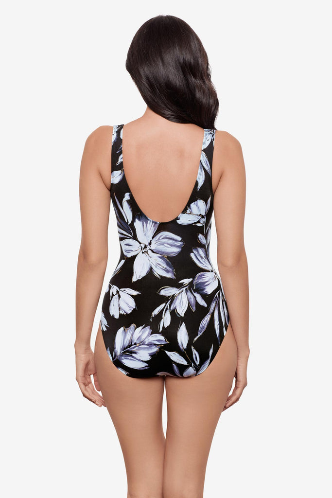 Woman turned away wearing a black and white floral printed one-piece swimsuit 