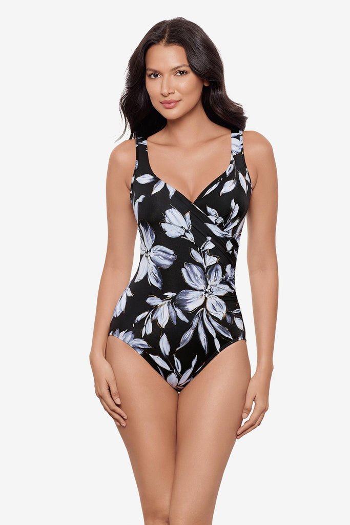 Woman wearing a black and white floral printed one-piece swimsuit with a sweetheart neckline