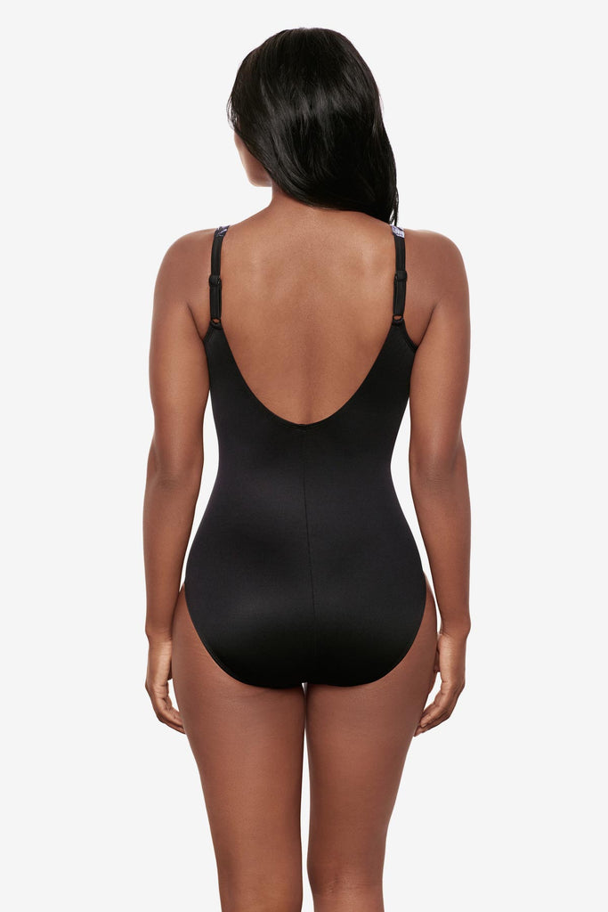Woman faced away wearing a black and white floral printed one-piece swimsuit