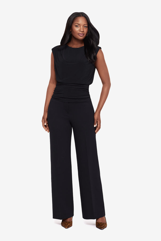 Woman in a black high neck blouse with matching wide leg pants