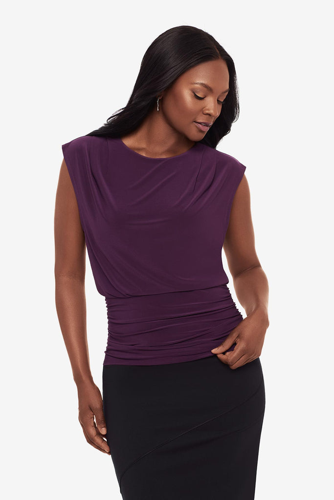 Close up of a woman wearing a plum-colored blouse with a black skirt