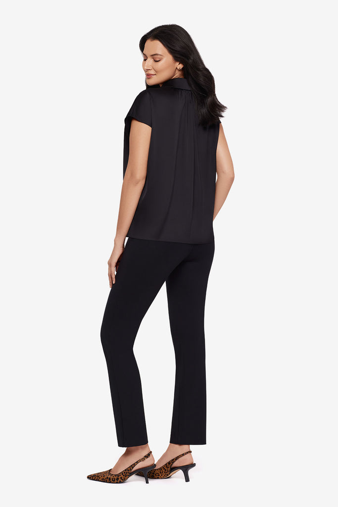 Woman turned left wearing a black blouse with matching black slim fit pants