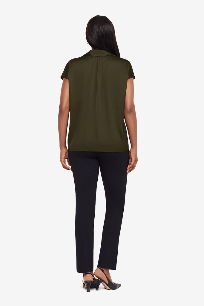 Woman turned away wearing a green button-down blouse with short sleeves and black dress pants