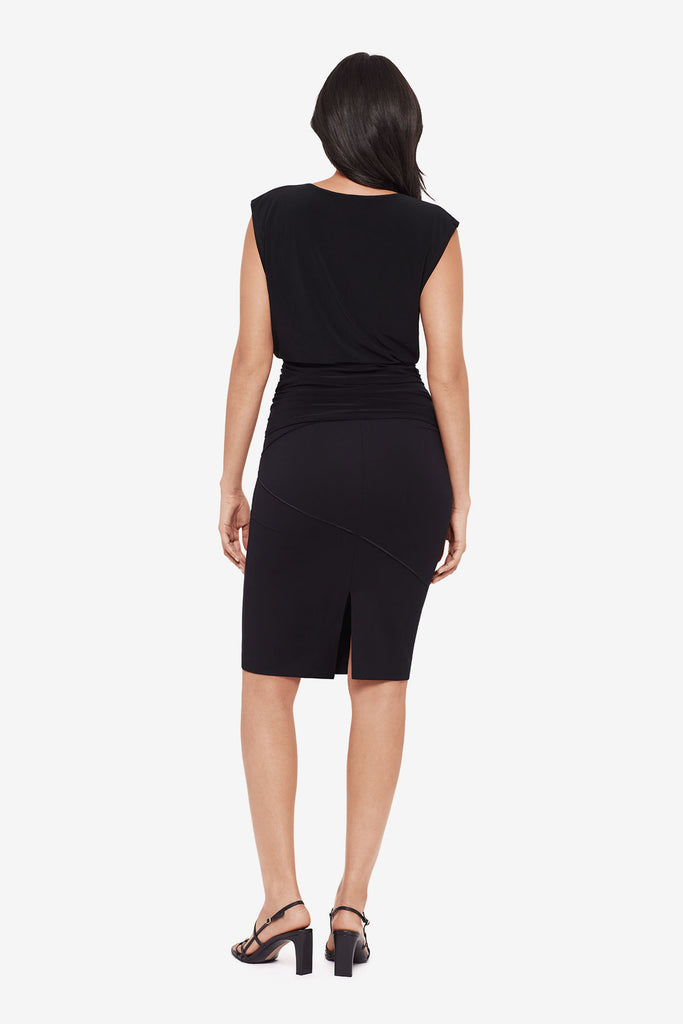 Woman turned away wearing a black tunic blouse with matching pencil skirt