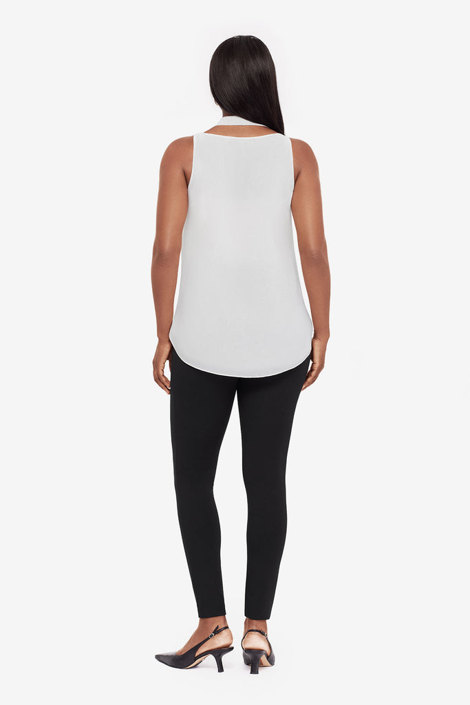 Woman turned away wearing a white tunic blouse with black leggings