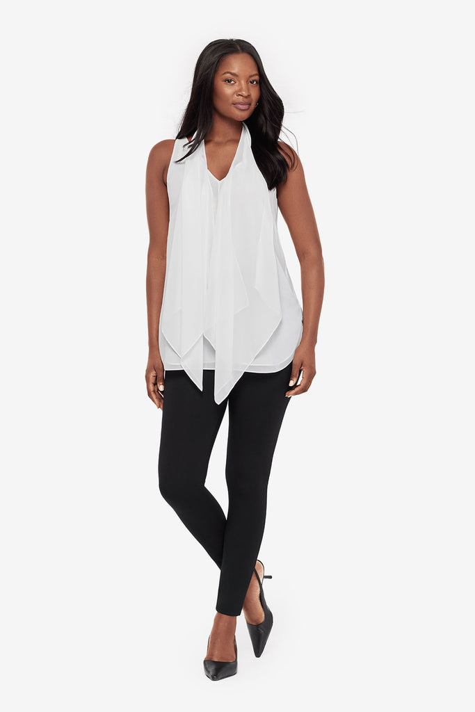 Woman wearing a white tunic blouse with black leggings