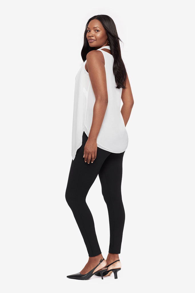 Woman turned left wearing a white tunic blouse with black leggings