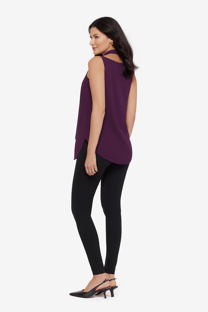 Woman turned left wearing a plum-colored tunic blouse with black leggings