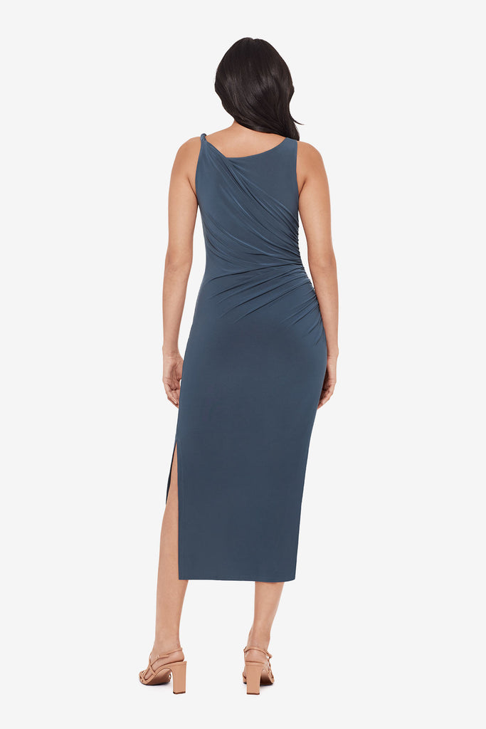 Woman turned away wearing a slate grey maxi dress with ruching on the side