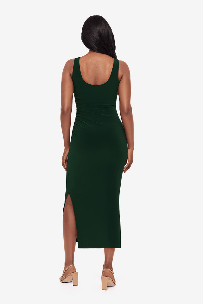 Woman turned away wearing a dark green maxi dress with slits on both sides