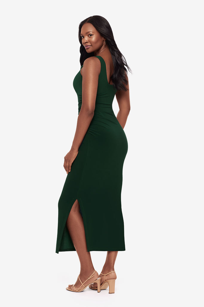 Woman turned left wearing a dark green maxi dress with slits on both sides
