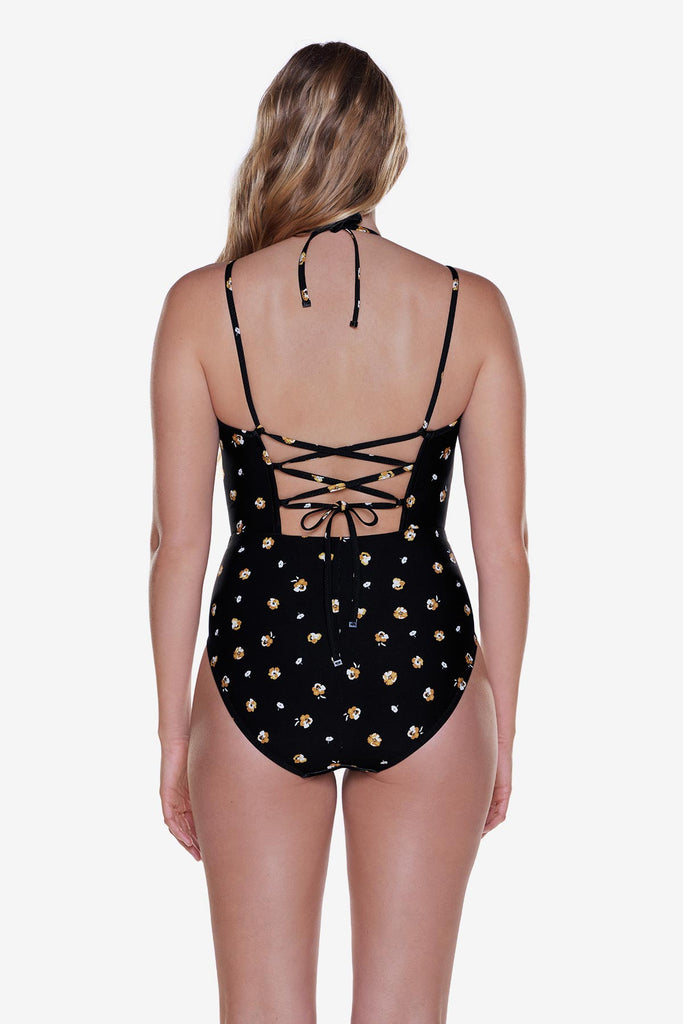 Woman turned away wearing a one-piece swimsuit with a small floral pattern and X tie back