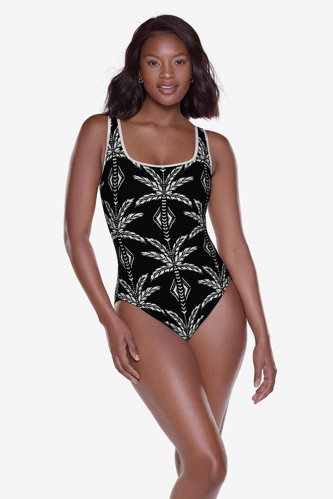 Woman wearing a black and white printed one-piece swimsuit with white piping