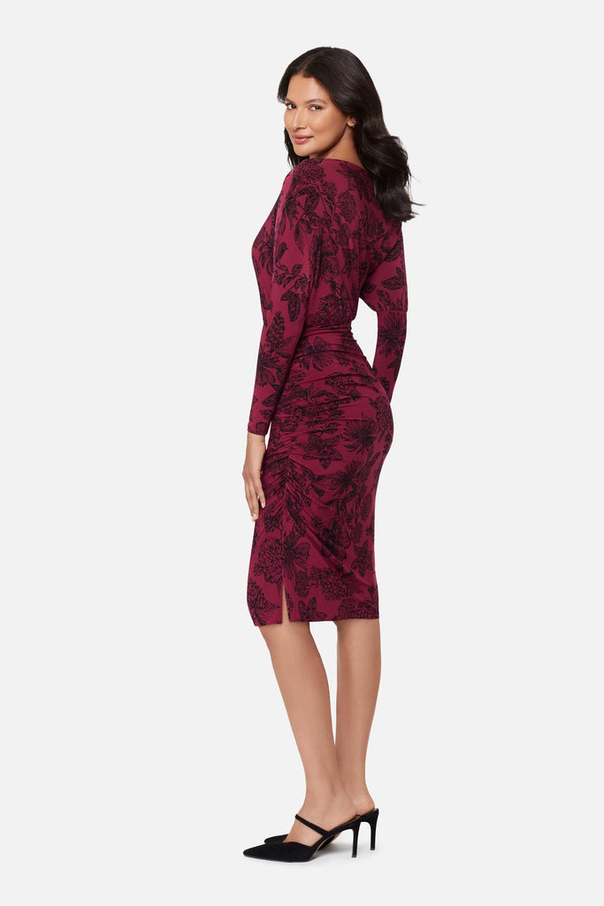 Woman turned left wearing a maroon long sleeve dress with a floral pattern