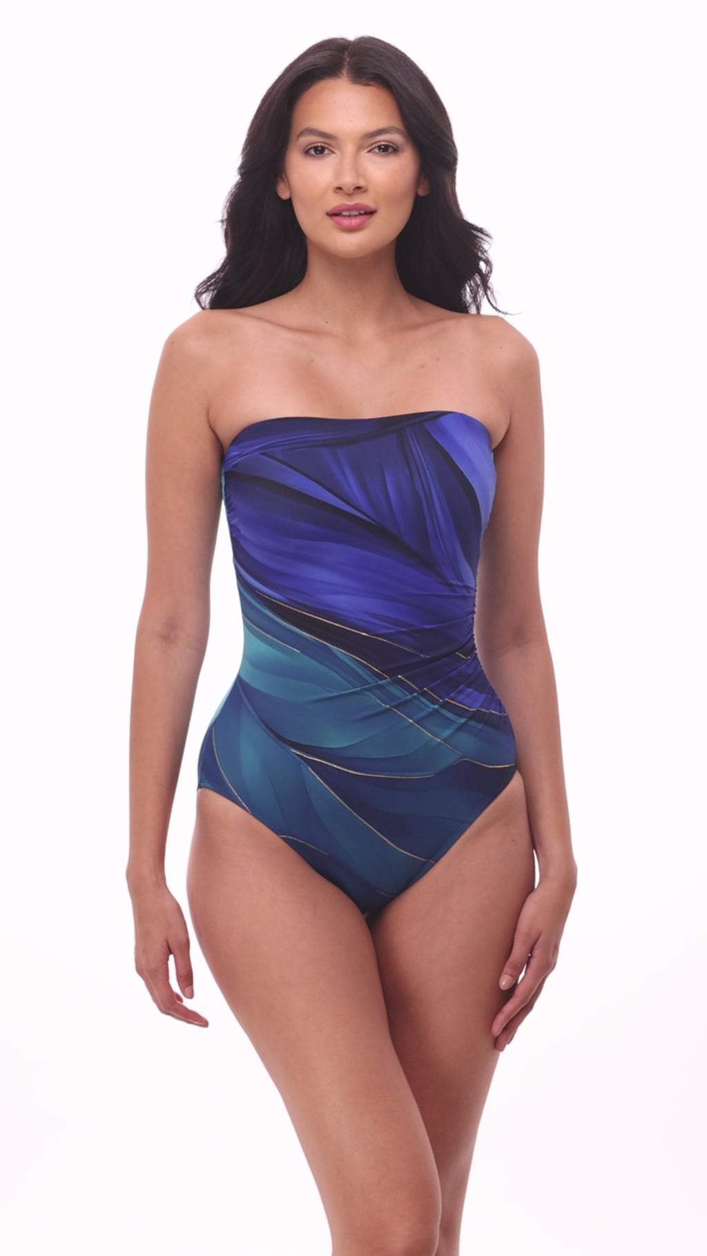 Woman wearing a multi-blue bandeau one-piece swimsuit with gold detail