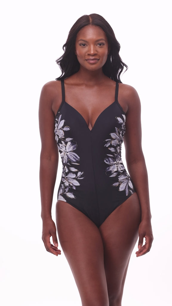 Woman wearing a black and white floral printed one-piece swimsuit with the design on each side